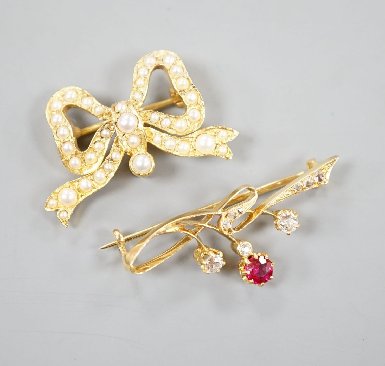 A yellow metal, ruby? and diamond set brooch, 36mm and a modern 9ct gold and split pearl set ribbon bow brooch, gross 8.5 grams.